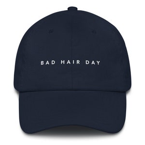 May include: A navy blue baseball cap with white embroidered text that reads "BAD HAIR DAY".
