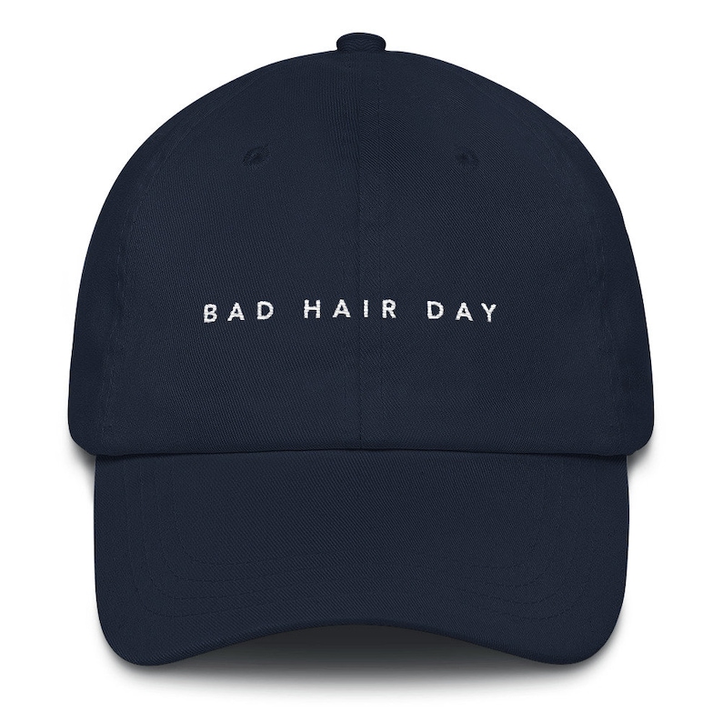 May include: A navy blue baseball cap with white embroidered text that reads "BAD HAIR DAY".