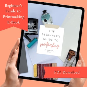 May include: A tablet displays a printmaking guide with supplies. The screen shows a book cover with the title "The Beginner's Guide to Printmaking" and the author's name. Printmaking ink, a brayer, and other tools are visible.