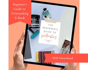 May include: A tablet displays a printmaking guide with supplies. The screen shows a book cover with the title "The Beginner's Guide to Printmaking" and the author's name. Printmaking ink, a brayer, and other tools are visible.