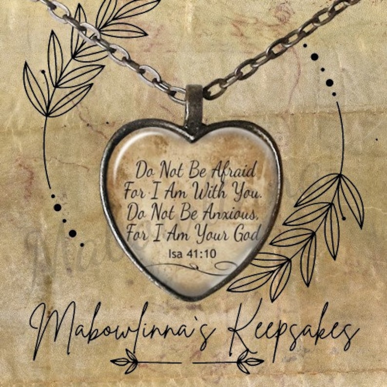 May include: A heart-shaped pendant necklace with a silver chain. The pendant has a clear glass center with the text "Do Not Be Afraid For I Am With You. Do Not Be Anxious. For I Am Your God Isa 41:10". The background has floral and leaf designs.