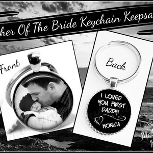 May include: A silver keychain with a black and white photo of a father and daughter on the front. The back of the keychain has the text "I loved you first daddy!" with a heart and the name "Monica".