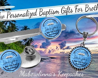 May include: A set of personalised baptism gifts for brothers. The gifts include a tie clip, a pin, a keyring, and a charm. Each gift features a blue and white design with a bible and the text "Dedicated to Jehovah" and "Best Life Ever!" with a date.