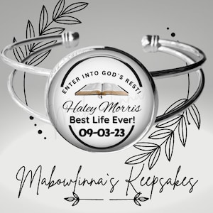 Pode incluir: Uma pulseira de punho prateada com um elemento central circular. Este elemento apresenta o texto "ENTER INTO GOD'S REST!", "Haley Morris Best Life Ever! 09-03-23" e uma imagem de um livro aberto. Motivos florais decoram a pulseira.