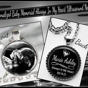 May include: A silver necklace with a round pendant. The front of the pendant features a black and white ultrasound image. The back of the pendant is black with white text that reads "Marie Ashley Always In My Heart 09-19-21".