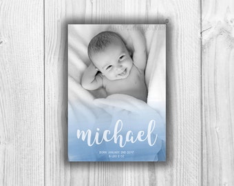 May include: A blue and white baby announcement card with a black and white photo of a baby boy. The card says "michael" in white cursive lettering and "Born January 2nd, 2017 8 lbs 2 oz" in black lettering.