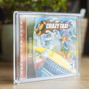 Puede incluir: Una funda de plástico transparente que contiene un disco de videojuego Sega Dreamcast. La portada del juego presenta el título "Crazy Taxi" con un taxi amarillo y personajes. El juego está clasificado "T" para adolescentes.