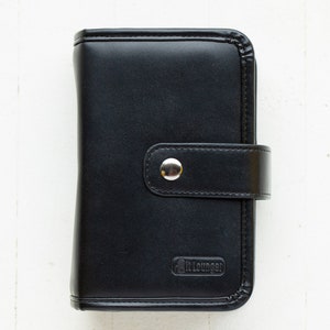 May include: A black leather wallet with a silver button closure and the word "itLounge" embossed on the front.