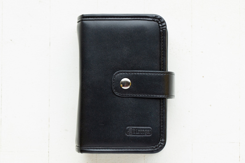 May include: A black leather wallet with a silver button closure and the word "itLounge" embossed on the front.
