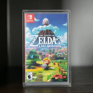 Pode incluir: Uma caixa de plástico transparente com um cartucho de jogo Nintendo Switch dentro. O jogo é The Legend of Zelda: Link's Awakening. A capa do jogo mostra um Link de desenho animado em pé em um campo verde com um céu azul e nuvens brancas no fundo.