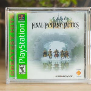 Könnte beinhalten: PlayStation-Spielhülle für Final Fantasy Tactics. Die Spielhülle befindet sich in einer transparenten Kunststoffschutzhülle. Das Cover zeigt eine Brückenszene mit Figuren auf Pferden. Der Rücken hat das PlayStation-Logo und "Greatest Hits".