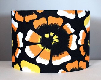 May include: A black lampshade with a repeating pattern of orange, yellow, and white flowers.