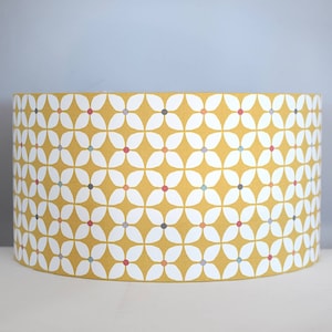 May include: A yellow lampshade with a white geometric pattern of flowers and small colored dots.