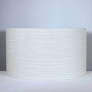 May include: A grey lampshade with a white wavy line pattern.