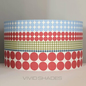 May include: A cylindrical lampshade with a geometric pattern of red, blue, and green circles. The lampshade is made of fabric and has a white background.