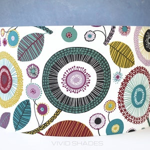 May include: A white drum lampshade with a colorful geometric pattern of circles, leaves, and dots in shades of teal, yellow, red, purple, and black. The pattern is reminiscent of a modern floral design.