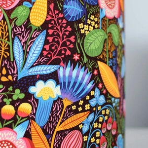 May include: A colorful lampshade with a floral pattern. The pattern features bright pink, yellow, blue, and green flowers on a dark brown background.
