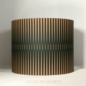 May include: A green and beige lampshade with a geometric pattern. The pattern features vertical stripes and a band of small circles.