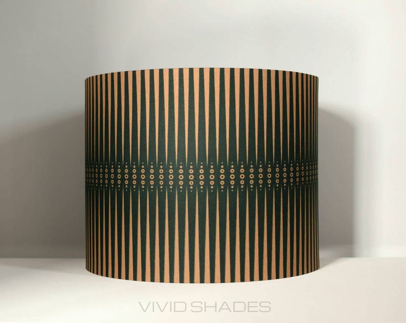 May include: A green and beige lampshade with a geometric pattern. The pattern features vertical stripes and a band of small circles.