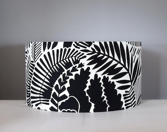 May include: A cylindrical lampshade featuring a bold black and white botanical leaf pattern. The design showcases various leaf shapes, creating a striking contrast against the white background. The lampshade is suitable for a table or floor lamp.