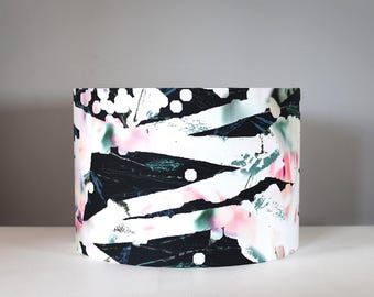 May include: A black and white lampshade with a pink and green abstract pattern.