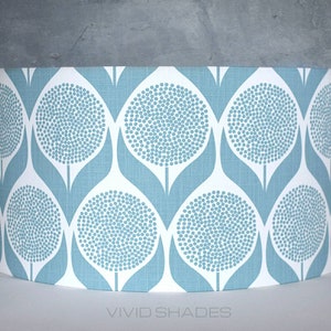 May include: A blue and white patterned lampshade with a repeating design of stylized flowers. The lampshade is cylindrical and has a white background with blue flowers.