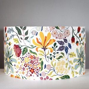 May include: A white lampshade with a colorful floral pattern. The pattern features yellow, red, blue, green, and purple flowers on a white background.