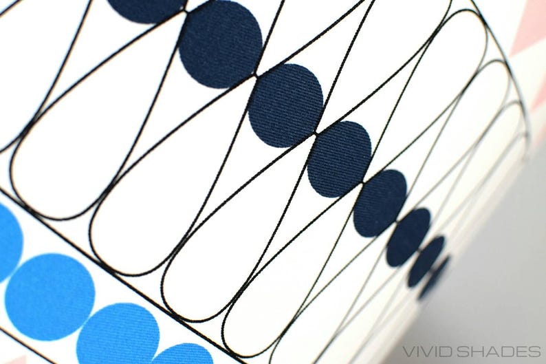 May include: A white fabric with a geometric pattern of black lines and blue and navy blue circles. The fabric is textured and has a subtle sheen.