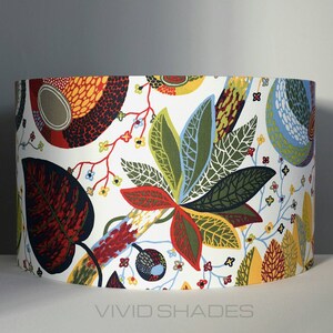 May include: A white lampshade with a colorful floral pattern featuring red, green, yellow, and blue leaves. The lampshade has a white background with a repeating pattern of stylized leaves and flowers.