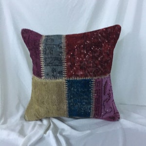 May include: A patchwork pillow cover with a variety of colors and patterns, including red, blue, purple, and beige. The pillow cover is made from recycled materials and has a unique, handmade look.