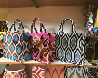 May include: Three tote bags with different ikat patterns. The bags are made of a soft, velvety fabric and have brown, blue, pink, and white colors.