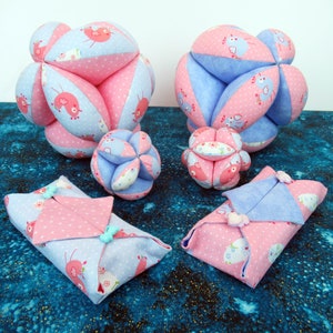 Puede incluir: Cinco bolas de tela hechas a mano en varios tamaños, con un esquema de color rosa y azul y un estampado de pájaros. Las bolas están hechas de tela suave y son perfectas para bebés y niños pequeños.