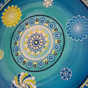 May include: A blue and green mandala with yellow and white dots. The mandala is surrounded by a border of black dots and white dots.
