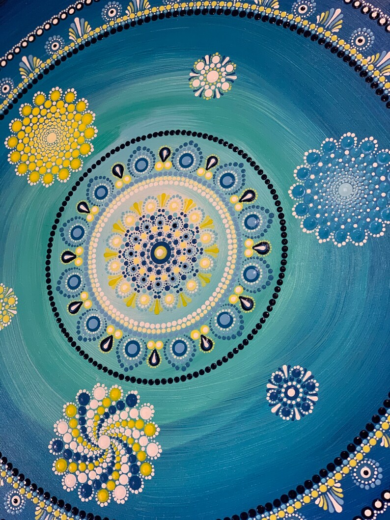 May include: A blue and green mandala with yellow and white dots. The mandala is surrounded by a border of black dots and white dots.