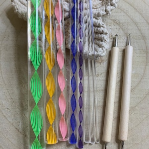 Peut inclure: Ensemble d'outils en acrylique transparent avec des motifs colorés. L'ensemble comprend des tiges vertes, jaunes, roses, bleues et transparentes, ainsi que deux outils de pointillage à manche en bois. Les tiges présentent un motif répétitif en forme de feuille.