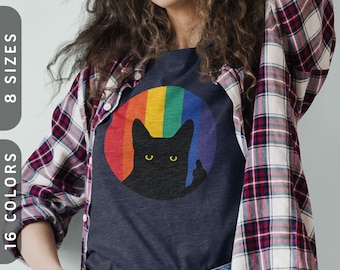 Könnte beinhalten: Ein marineblaues T-Shirt mit einem Regenbogenkreis und einer schwarzen Katzensilhouette, die den Mittelfinger zeigt. Die Katze hat gelbe Augen.