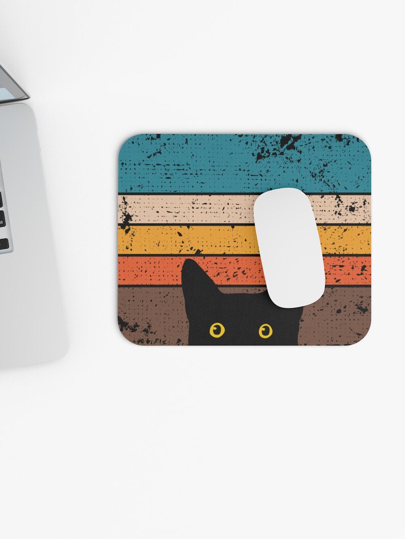 May include: A black cat with yellow eyes peeks out from behind a retro-style striped mouse pad. The mouse pad has a distressed, vintage look with faded blue, orange, yellow, and brown stripes.