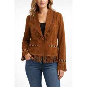 May include: A brown suede jacket with fringe detailing on the collar, pockets, and cuffs. The jacket has a button closure and decorative beading on the cuffs and pockets. The jacket is worn with blue jeans.