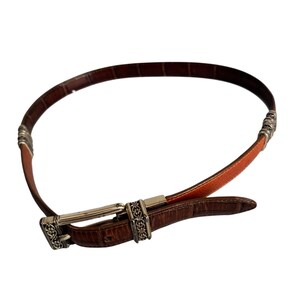 Peut inclure: Une ceinture marron avec un motif textur&eacute; gaufr&eacute; fa&ccedil;on crocodile, dot&eacute;e d'une boucle en m&eacute;tal argent&eacute; et de deux passants d&eacute;coratifs en m&eacute;tal argent&eacute; avec des d&eacute;tails en filigrane. La sangle pr&eacute;sente une section en cuir lisse beige.