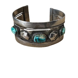 Può includere: Bracciale in argento con pietre turchesi incastonate in una fascia d'argento. Il bracciale presenta un design intrecciato ed è un classico gioiello nativo americano.
