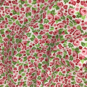 以下が含まれることがあります： ピンクと緑の花柄の白い生地。生地は小さなピンクのバラと緑の葉で覆われています。