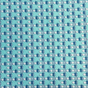 Puede incluir: Tela azul aguamarina con un patrón repetido de muñecas kewpie blancas y azules. La tela tiene un borde blanco con el texto "Aunt Grace Simply Charming" y "Judie Rothermel" en texto negro. El texto "Kewpie Doll" también está en texto negro.
