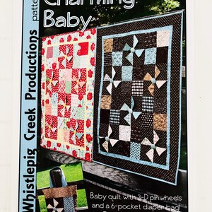 May include: A sewing pattern titled Charming Baby by Whistlepig Creek Productions #1146. The cover features two baby quilts with 3-D pinwheels and a 6-pocket diaper bag. The quilts display red floral and brown polka dot fabric patterns.