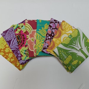 Puede incluir: Una colección de cuadrados de tela doblados en varios colores y estampados florales. Las telas incluyen tonos de naranja, morado, verde, rosa y amarillo. Los estampados incluyen flores grandes, hojas y diseños abstractos. Las telas están dispuestas en forma de abanico.