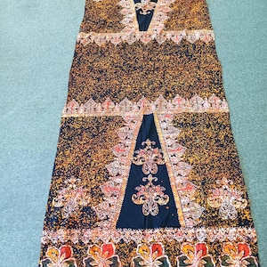 May include: A rectangular fabric panel featuring a dark navy blue base with a dense orange and yellow speckled pattern. The design includes two large triangular sections with intricate floral motifs and a bottom border of five large hibiscus flowers.