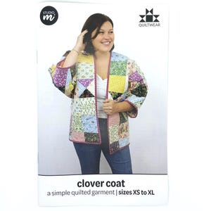 May include: A woman wearing a patchwork quilted clover coat. The coat is open, revealing a white top and blue jeans. The coat features a variety of colorful fabric squares. The packaging includes the text "clover coat" and "a simple quilted garment | sizes XS to XL."