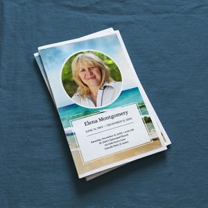 May include: A pile of memorial cards with a photo of a woman in a circular frame, set against a beach scene. The card includes the name "Elena Montgomery" and dates. Text at the bottom reads "Editable memorial & funeral templates honoring a life lived in colour."