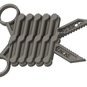 May include: A gray metal multi-tool with a snake and scissor design. The tool is folded up and has a ring on each end.