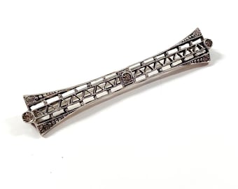 May include: A silver brooch with a geometric design and small clear stones.