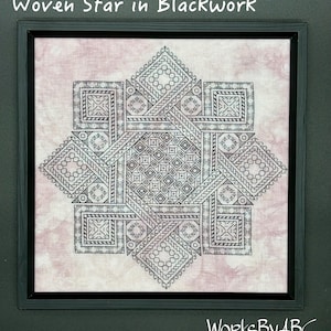 Può includere: Ricamo blackwork incorniciato con un design a stella geometrica. L'opera, intitolata "Woven Star in Blackwork", mostra intricati motivi in filo nero su uno sfondo beige rosato. Il pezzo è racchiuso in una cornice nera, con la firma dell'artista in basso.